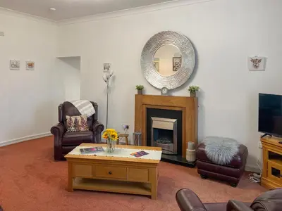 a living room with a fireplace and a mirror at Muirston Farmhouse - Uk44977 in Ayr