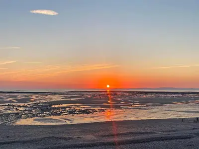 a sunset on the beach with the sun setting at The Police Station - Uk45642 in Silloth