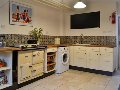 a kitchen with a washing machine and a tv on the wall at Clachries Cottage in Boreland of Colvend