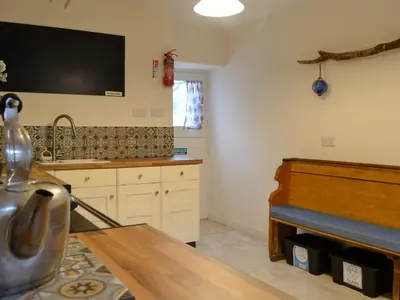 a kitchen with a table and a tv on the wall at Clachries Cottage in Boreland of Colvend
