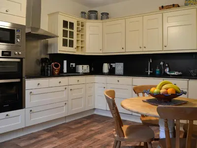 a kitchen with a table with a bowl of fruit on it at Clachries Cottage in Boreland of Colvend