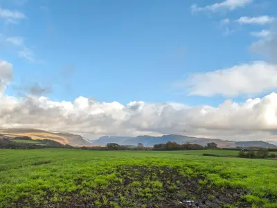 a green field with mountains in the background at Harebeck Cottage in Gosforth