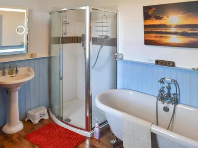 a bathroom with a bath tub and a sink at Harebeck Cottage in Gosforth