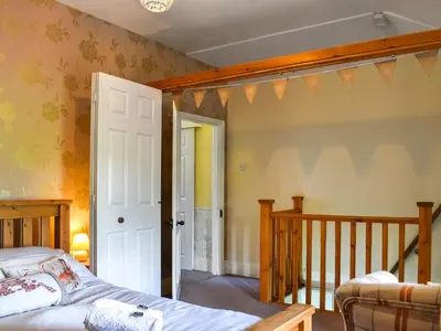 a bedroom with a bed and a staircase in a room at Harebeck Cottage in Gosforth