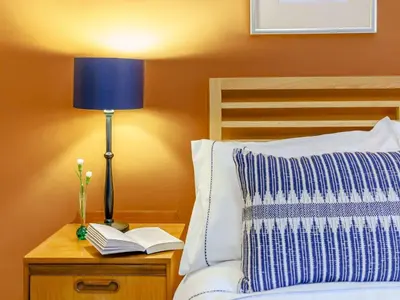 a bed with a blue lamp and books on a nightstand at 2 Bed in Cockermouth 86528 in Arlecdon