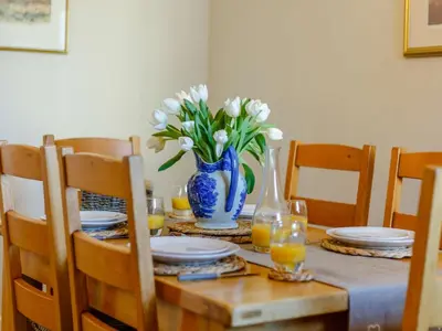 a dining room table with a blue vase with white flowers at 3 Bed in Bridekirk 85717 in Bridekirk