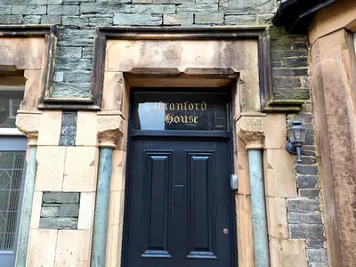 a black door in a stone building with a sign above it at Cranford House in Keswick