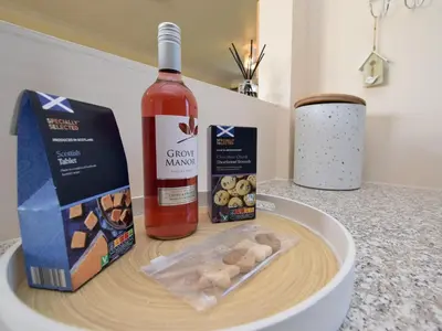 a bottle of wine and a box of cookies and a bottle of food at 2 Bed in Isle of Whithorn 77880 in Isle of Whithorn
