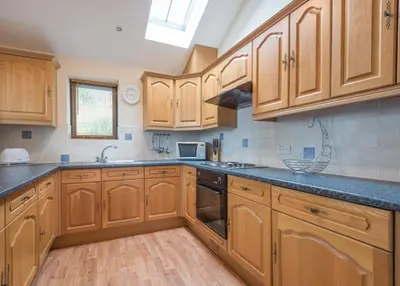 a kitchen with wooden cabinets and black counter tops at 3 Bed in Threlkeld SZ433 in Threlkeld