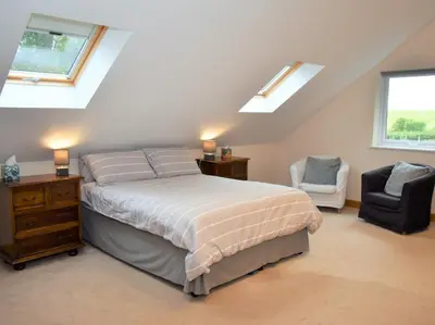 a bedroom with a bed and a chair and windows at 1 Bed in Grinsdale Bridge 85163 in Carlisle
