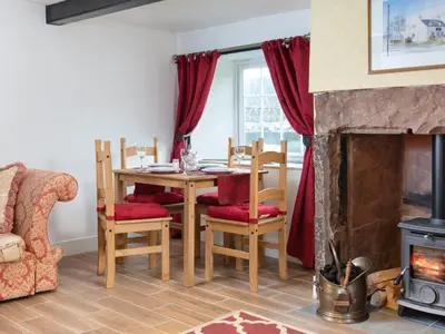 a dining room with a table and chairs and a fireplace at 2 Bed in Mawbray SZ214 in Mawbray