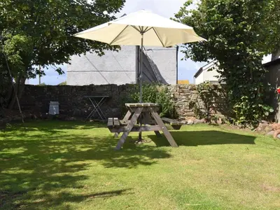 a picnic table with an umbrella in a yard at 2 Bed in Mawbray SZ214 in Mawbray