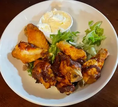a plate of food with chicken wings and a salad at The Herdwick Inn in Penruddock