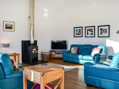 a living room with blue couches and a fireplace at The Longhouse At Threave in Castle Douglas