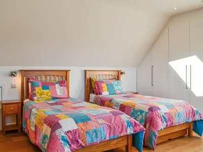 two beds in a bedroom with white walls at The Longhouse At Threave in Castle Douglas