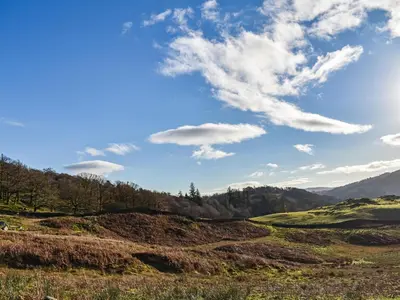 a grassy hill with a blue sky and clouds at Lingmoor View in Ambleside