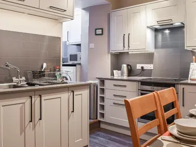 a kitchen with white cabinets and a table and a chair at Lingmoor View in Ambleside