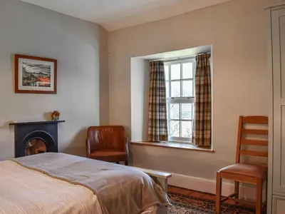 a bedroom with a bed and a window and two chairs at Lingmoor View in Ambleside