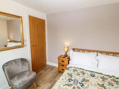 a bedroom with a bed and a chair and a mirror at Cherry Croft in Wigton