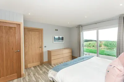 a bedroom with a large bed and a window at High Tide Lodge in Gatehouse of Fleet