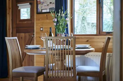 a dining room table with a vase of flowers on it at Buzzard Lodge with Hot-tub in Carlisle