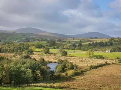 a river in a field with mountains in the background at 1 Bed in Matterdale SZ222 in Watermillock