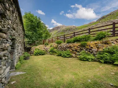 a stone wall with a fence and a grass field at 3 Bed in Seathwaite SZ107 in Eskdale