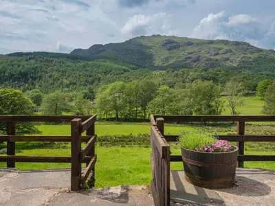 a wooden fence with a pot of flowers on a field at 3 Bed in Seathwaite SZ107 in Eskdale