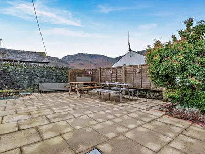 a patio with a table and benches and a fence at 2 Bed in Rosthwaite 86397 in Rosthwaite
