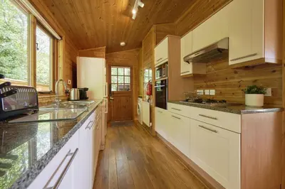 a kitchen with white cabinets and a wooden ceiling at Egret Lodge with Hot-tub in Carlisle