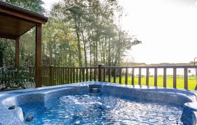 a jacuzzi tub sitting on a deck with a porch at Egret Lodge with Hot-tub in Carlisle