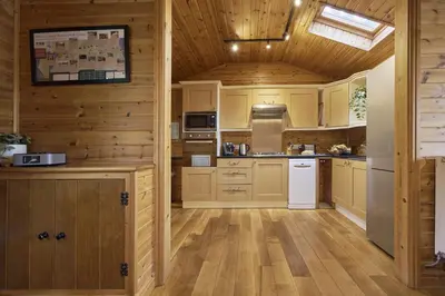 a large kitchen with wooden walls and wooden floors at Fieldfare Lodge with Hot-tub in Carlisle