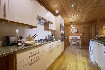 a kitchen with white cabinets and a wooden ceiling at Gadwall Lodge with Hot-tub in Carlisle