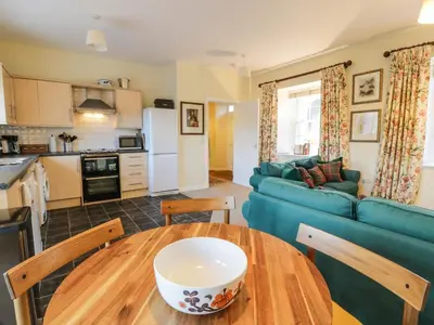 a kitchen and living room with a table and a blue couch at The Stables in Dumfries