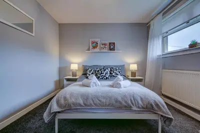 a bedroom with a large bed with two night stands at Ravenscroft - Coorie Doon in Irvine