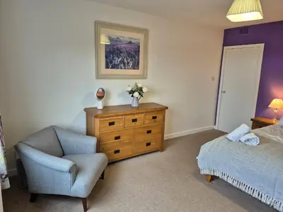 a bedroom with a bed and a chair and a dresser at 3 Bed in Auldgirth 77430 in Auldgirth