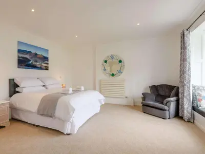 a white bedroom with a bed and a chair at 4 Bed in Keswick oc-87567 in Keswick