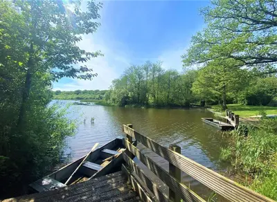 a boat on a river next to a wooden bridge at Alder Lodge with Hot-tub in Carlisle