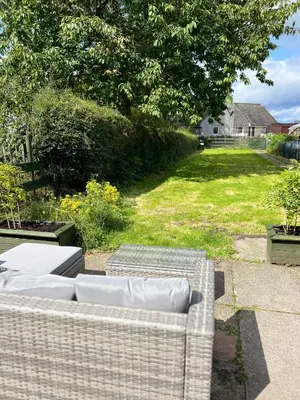 a couch sitting on a patio with a yard at The Ship Inn's Mill Cottage - Weavers Way in Gatehouse of Fleet