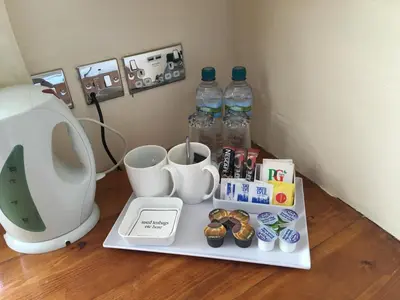 a table with cups and bottles of water and donuts at Cubbon House in Douglas