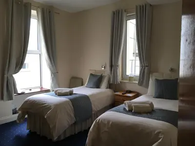 two beds in a room with two windows at Cubbon House in Douglas