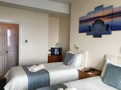 a hotel room with two beds and a couch at Cubbon House in Douglas