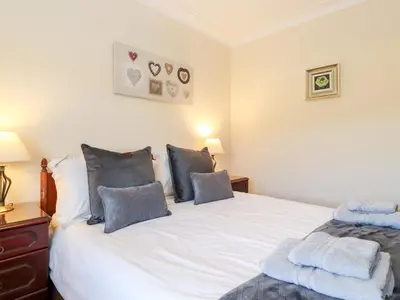 a bedroom with a large white bed with blue pillows at Rainbow End in Ambleside