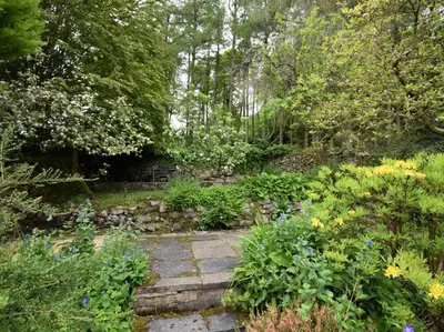 a garden with a stone path with flowers and trees at 3 Bed in Eskdale SZ416 in Santon Bridge