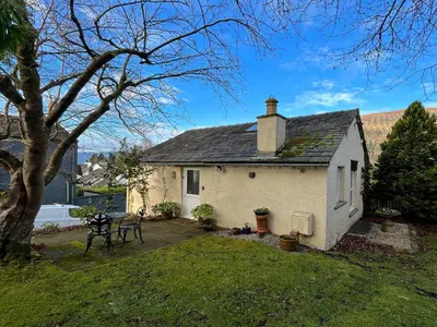 a small white house in a yard with a tree at 1 Bed in Keswick SZ516 in Keswick