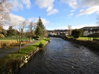 a river with a stone wall next to a street at 2 Bed in Keswick oc-sz006 in Keswick
