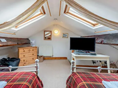 a attic bedroom with a flat screen tv and two beds at 3 Bed in Ullock SZ043 in Arlecdon
