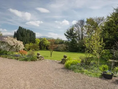 a garden with three stone statues sitting in the grass at 3 Bed in Pardshaw SZ419 in Dean