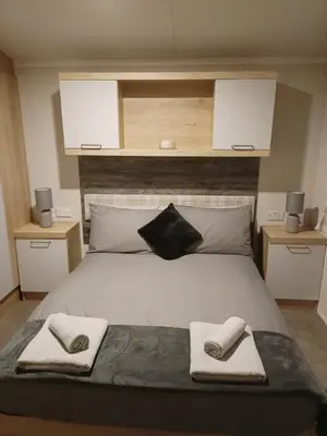 a bedroom with a large bed with towels on it at Hillingworth's Hot Tub Retreat - Lochmaben in Dumfries