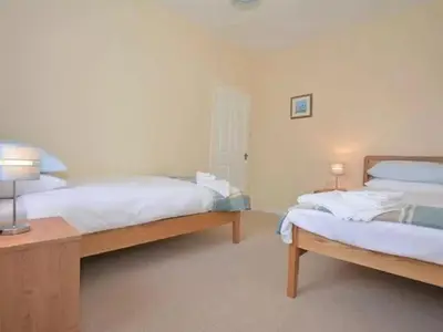 a bedroom with two beds and a table with two lamps at Criffel View in Dumfries